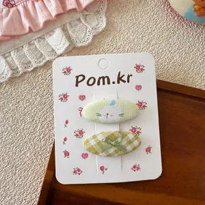Détail de barrettes en tissu avec motif chat et nœud papillon en deux pièces