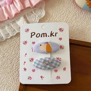 Détail de barrettes à motif chien et nœud à carreaux sur une carte décorative