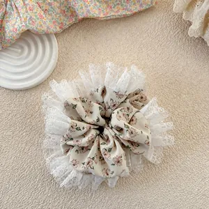 Detail view of floral fabric hair scrunchie with delicate double-layered lace edges