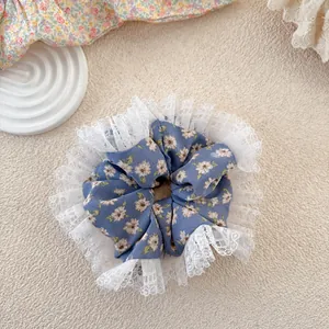 Close-up of floral scrunchie in dusty blue with white lace trim and daisy pattern