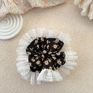 Close-up of floral fabric hair scrunchie with lace trim on a soft cream background