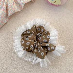Close-up of floral fabric hair scrunchie with layered white lace trim and brown petals