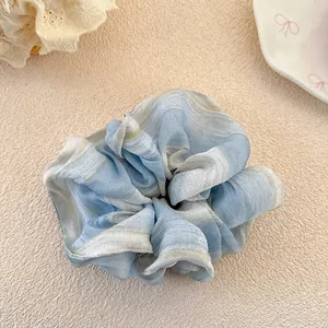 Detailed macro view of a light blue gradient striped chiffon fabric scrunchie