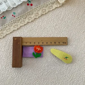 Détail de barrettes en tissu avec décor de tulipe et broderie cerise sur texture