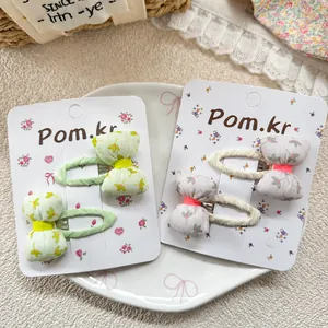 Floral bow hair clips for girls featuring cute sweet patterns on a decorative ceramic plate