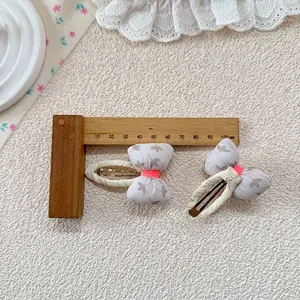 Close-up of floral bow hair clips with leaf patterns and pink ribbon center detail