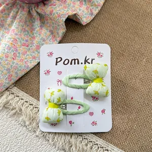 Close-up of a pair of sweet floral bow hair clips for girls on a paper display card