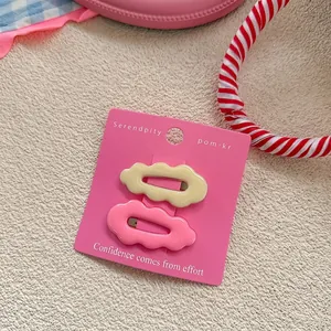 Detail of wavy cloud-shaped hair clips in pastel yellow and pink colors on display card
