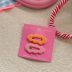 Detail view of wavy candy-colored hair clips in pink and orange on a display card