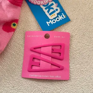 Gros plan de deux barrettes triangle rose mat sur carte pour coiffure de frange