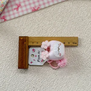 Detail of pink embroidered cartoon hair tie with lace flowers and plush ball decoration