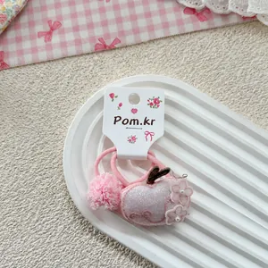 Detail of pink Korean style hair tie with sequin apple embroidery and plush pom-pom