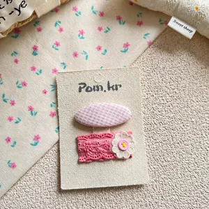 Détail de barrettes à cheveux roses à carreaux et dentelle sur carte de présentation