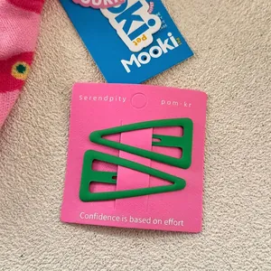 Gros plan de pinces à cheveux triangulaires vert mat sur carte rose