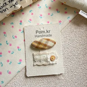 Détail de la pince à cheveux en tissu et épingle fleur en dentelle avec bouton en bois
