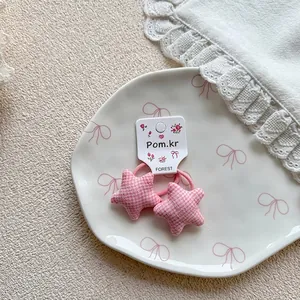 Close-up of pink plaid star hair ties on a ceramic plate with white lace decor
