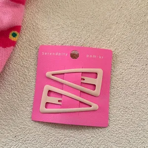 Détail de deux pinces à cheveux triangles rose mat sur carte de présentation
