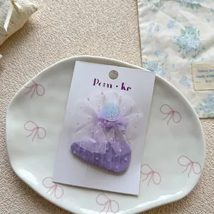 Detail of purple polka dot bow hair clip with sequins on a branded display card
