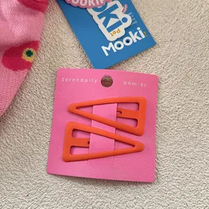 Détail de barrettes à cheveux orange mat en forme de triangle irrégulier sur carte