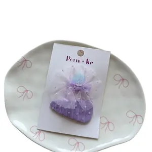Purple fabric bow hair clip with sequins and tulle for girls on a white display card