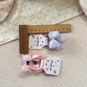 Detail of sweet bow hair ties set in pink and purple with mesh fabric and floral beads
