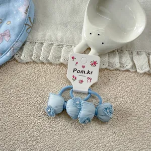 Detail of light blue bow hair tie with floral patterns and pearl on lace fabric