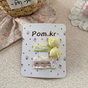 Detail of sweet floral embroidered yellow bow hair clip and pink checkered star clip