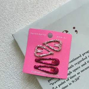 Detail of four glitter hair clips in heart and water drop shapes on a display card