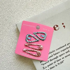 Close-up of four glitter hair clips including heart and water drop shapes on card