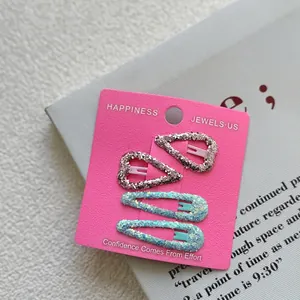 Detail of four glitter heart and water drop hair clips on a pink display card