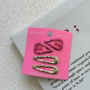 Set of 4 glitter hair clips including pink hearts and gold oval pins on a display card