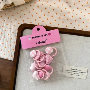 Détails d'un lot d'élastiques à cheveux roses avec cœur en tissu et boutons à carreaux