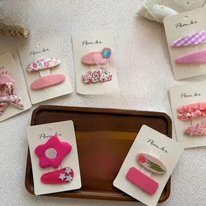 Détail des barrettes pour filles en tissu floral rose et paillettes sur support