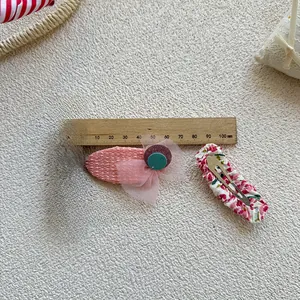 Détail des barrettes à fleurs roses et paillettes mesurant 50 mm sur un fond en maille