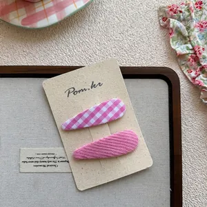 Vue détaillée de deux barrettes à fleurs roses et à carreaux sur une carte support