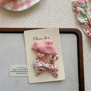 Détail de barrettes à cheveux avec nœuds en tissu floral et rose sur une carte de support
