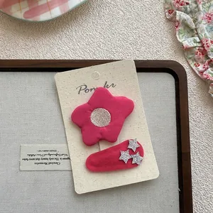 Gros plan sur barrette à fleur rose en tissu et clip à étoiles style fille mignonne