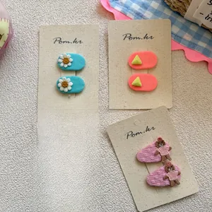 Dettaglio di fermagli in tessuto ricamato per bambini con motivi di margherite e orsi
