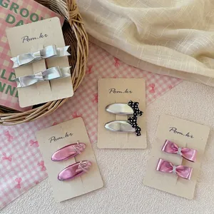 Set di quattro graziosi fermagli per capelli con fiocco metallico per bambine su eleganti carte