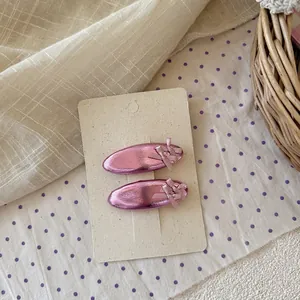 Dettaglio di due fermagli per capelli in metallo rosa con fiocchi su carta display