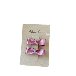 Set di due fermagli per capelli a fiocco rosa metallizzato per bambine su carta