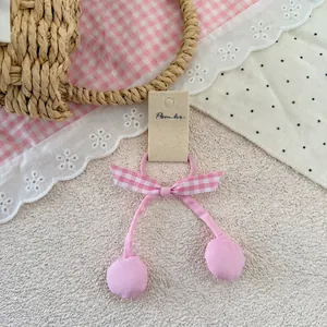 Détail d'un élastique rose avec nœud à carreaux et pendentifs en boules de tissu
