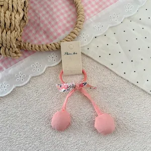 Détail d'élastique à cheveux cerise rose avec nœud floral et étiquette sur dentelle