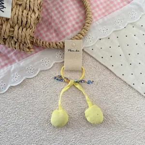 Détail de l'élastique à cheveux cerise jaune avec nœud floral sur carte de support
