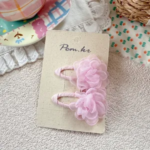 Close-up of pink tulle flower hair clips with fabric wrapped duckbill clips on card