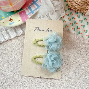 Close-up of light blue mesh flower hair clips on beige display card with floral background
