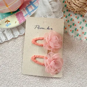 Close-up of pink fabric flower hair clips with coral BB clips on a display card