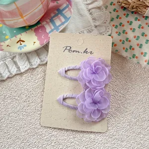 Detail of two lavender layered organza flower BB hair clips on a cream display card
