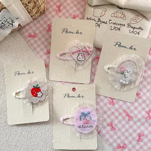 Close-up of four Korean-style embroidered lace hair clips with cherry and rabbit motifs