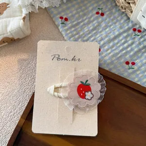 Close-up of red strawberry embroidery hair clip with white floral center and lace trim